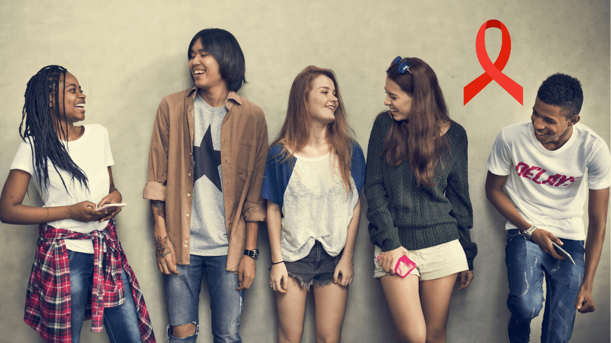 A group of diverse young adults standing together and smiling, with a red HIV awareness ribbon displayed nearby