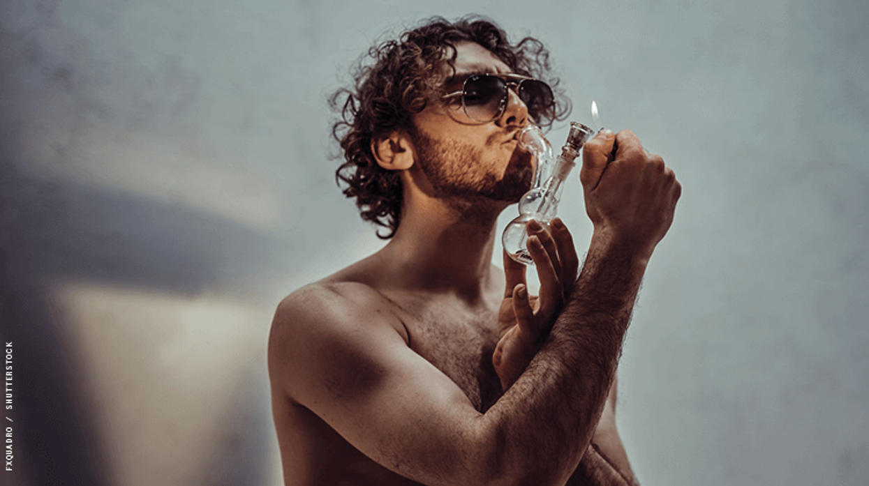 a shirtless man smoking weed through a bong