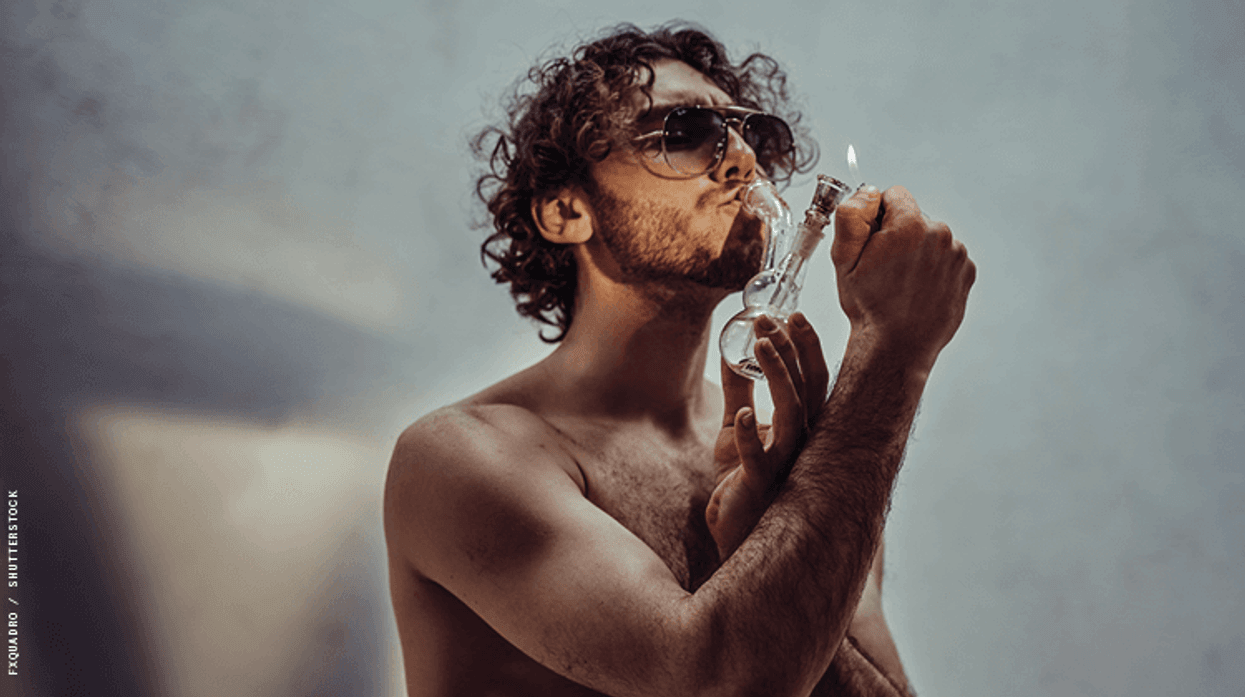a shirtless man smoking weed through a bong