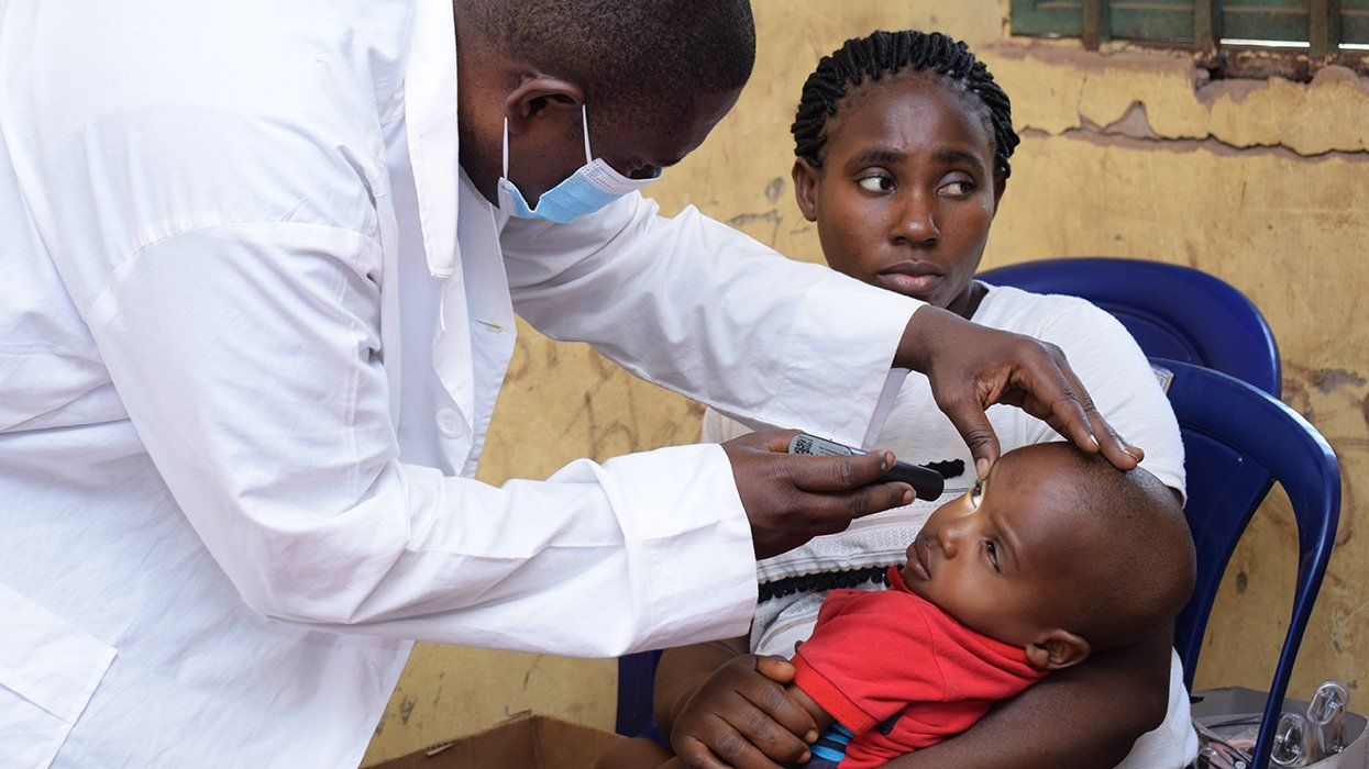 africa Medical Doctor giving treatment to child in mothers lap in Rural clinic Abuja Nigeria