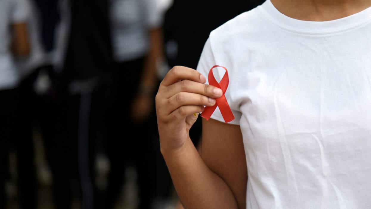 Black woman holding red HIV ribbon