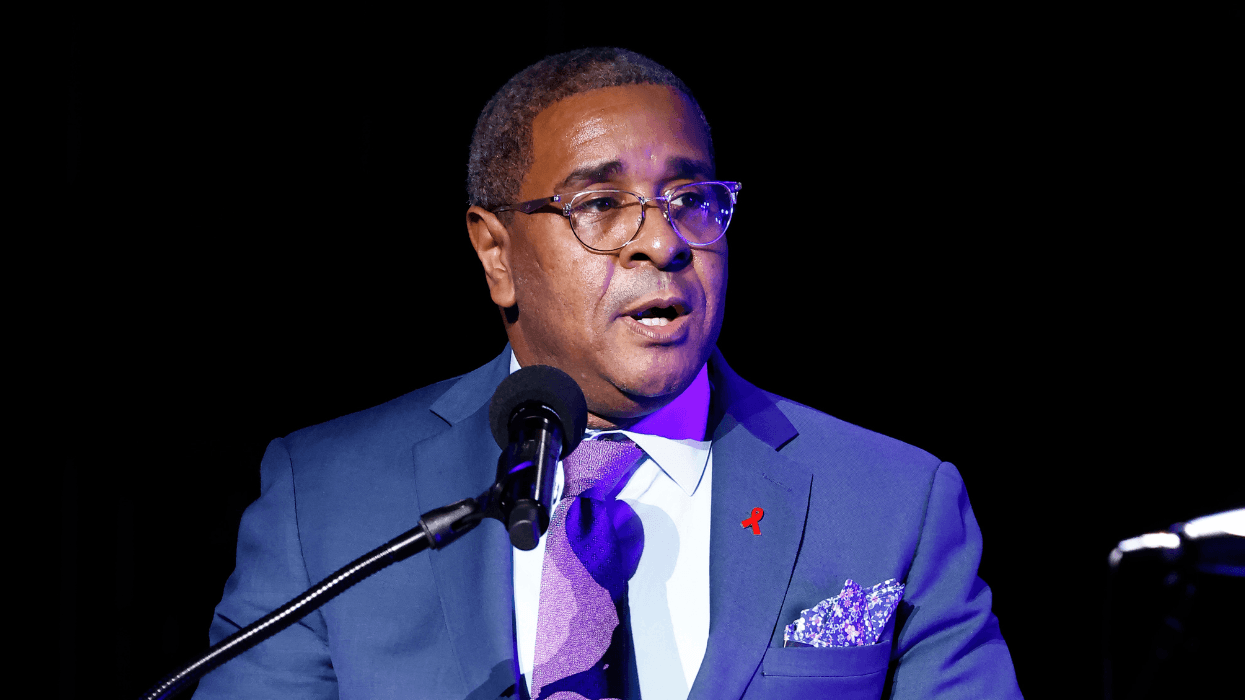 Harold J. Phillips speaks at a podium during a World AIDS Day event in Washington, D.C., wearing a blue suit with a red ribbon