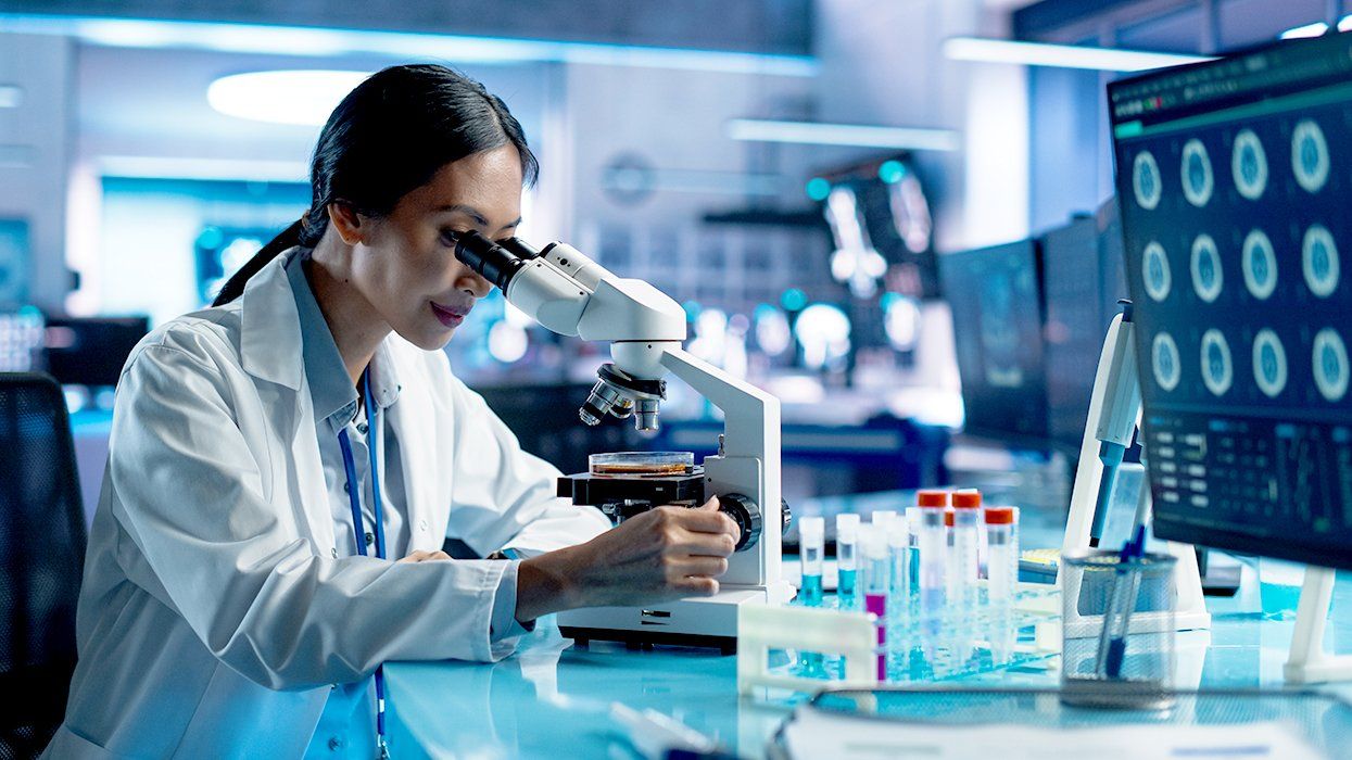 Scientist conducting lab research looking in microscope