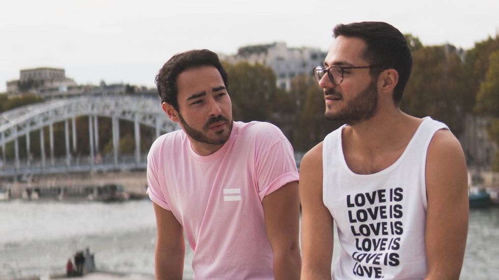 Two young men sitting outside near the water